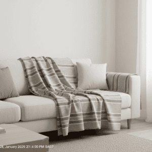 Cozy living room featuring a beige sofa, neutral cushions, and a striped throw blanket, illuminated.