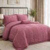 Five-piece pink queen quilt bedding set with matching shams and decorative pillows.